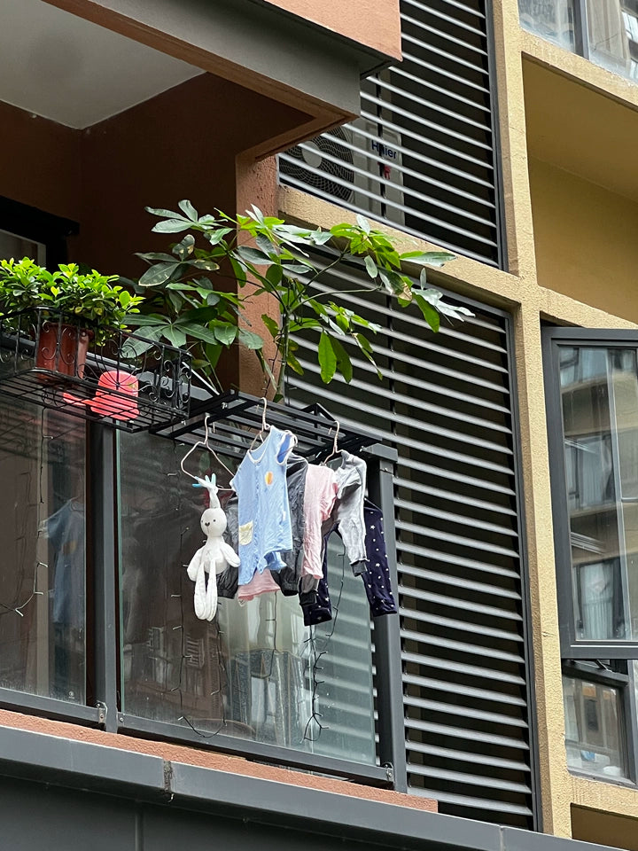Séchoir à linge de balcon Easerack avec vêtements de bébé et peluche.