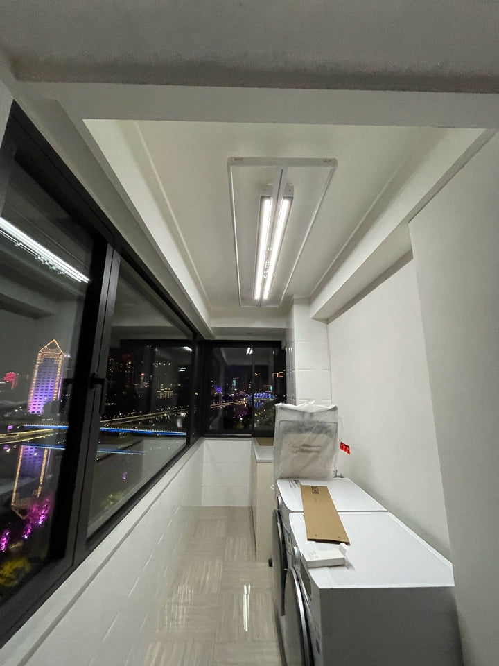 EaseRack X9 Mini ceiling drying rack with integrated LED light, mounted on a balcony with city night view.