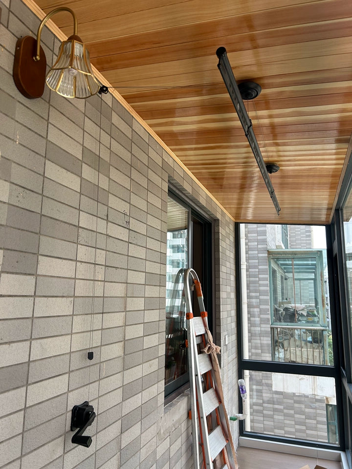 Clothes drying rack installed on a wooden ceiling balcony with vintage lighting