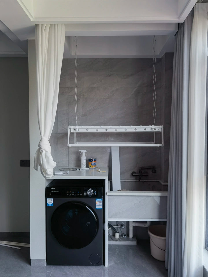 White electric drying rack installed in laundry area with washing machine underneath.