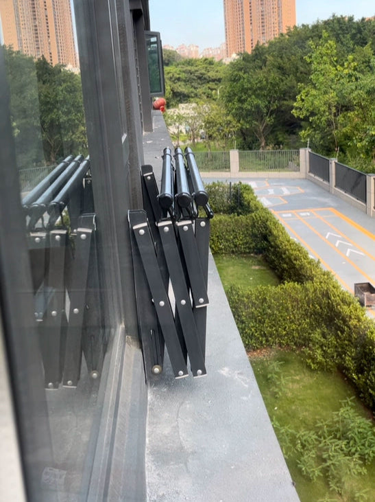 Compact folding clothes drying rack mounted outside a window, ideal for apartment residents with limited balcony space.