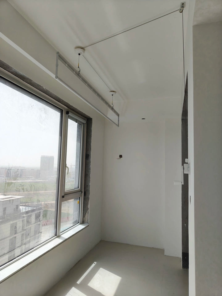 Minimalist balcony with a ceiling-mounted clothes drying rack and large window lighting.