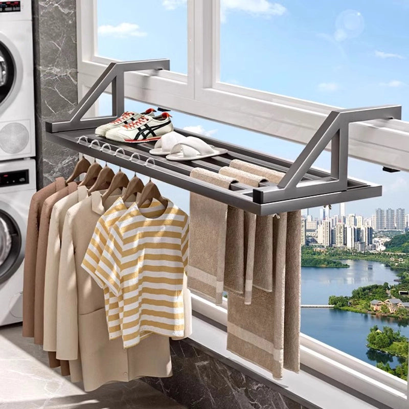 Window-mounted clothes drying rack installed on a balcony, holding shirts, jackets, and towels.