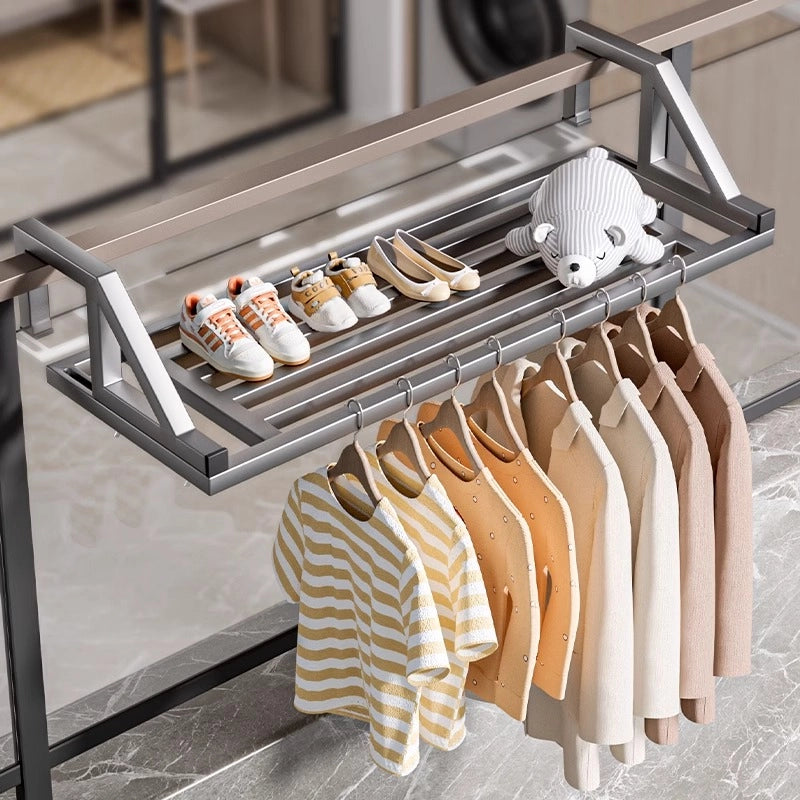 Heavy-duty clothes drying rack fully loaded with shirts, jackets, and children’s shoes, mounted on a window railing.