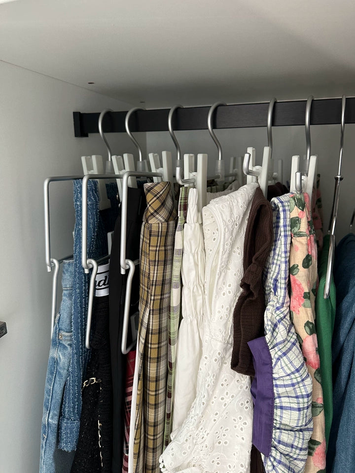 Aluminum adjustable clip hangers holding pants and skirts on a closet rail for organized storage