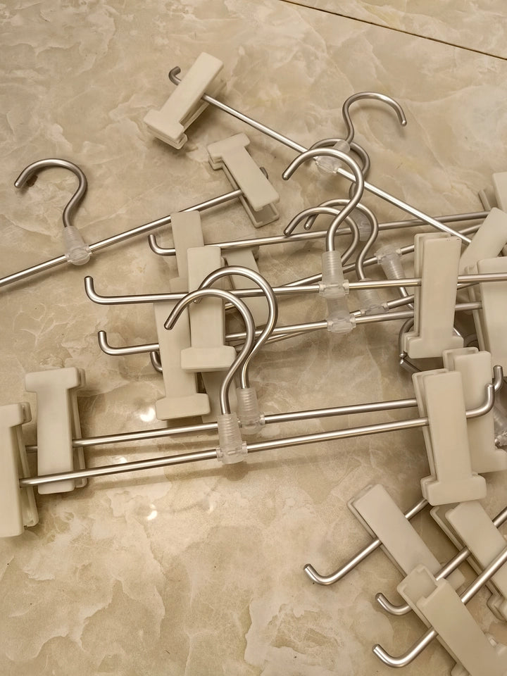 Aluminum adjustable clip hangers with white no-mark clips and metal hooks on a tabletop