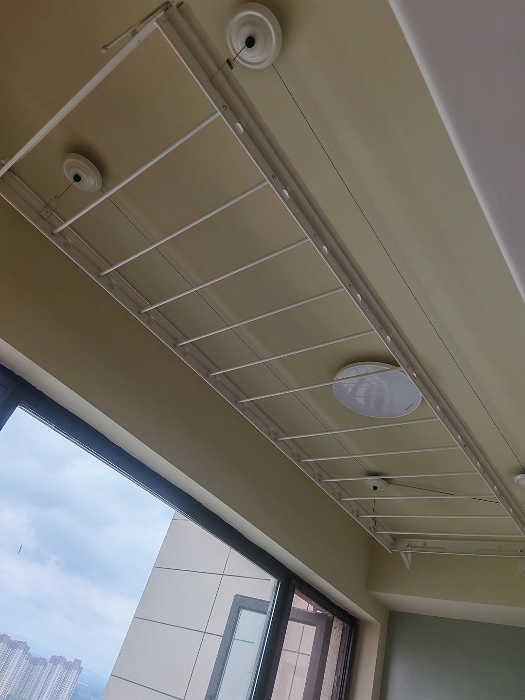 Ceiling clothes airer installed on a covered balcony, showing the suspended frame and ceiling fixing points