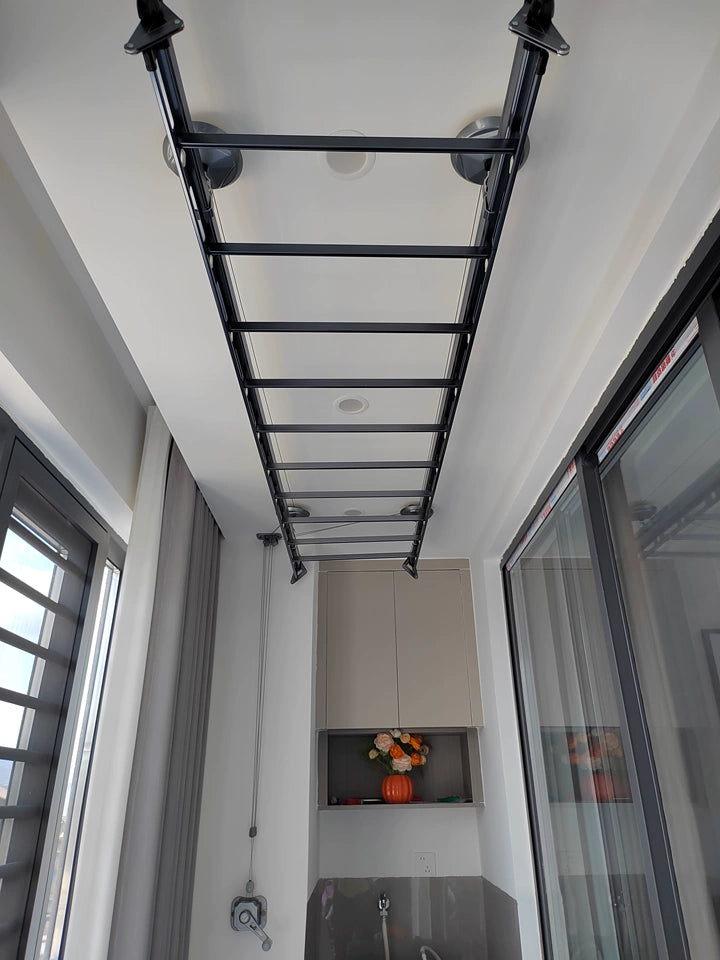Ceiling-mounted manual clothes drying rack installed in bright indoor laundry balcony