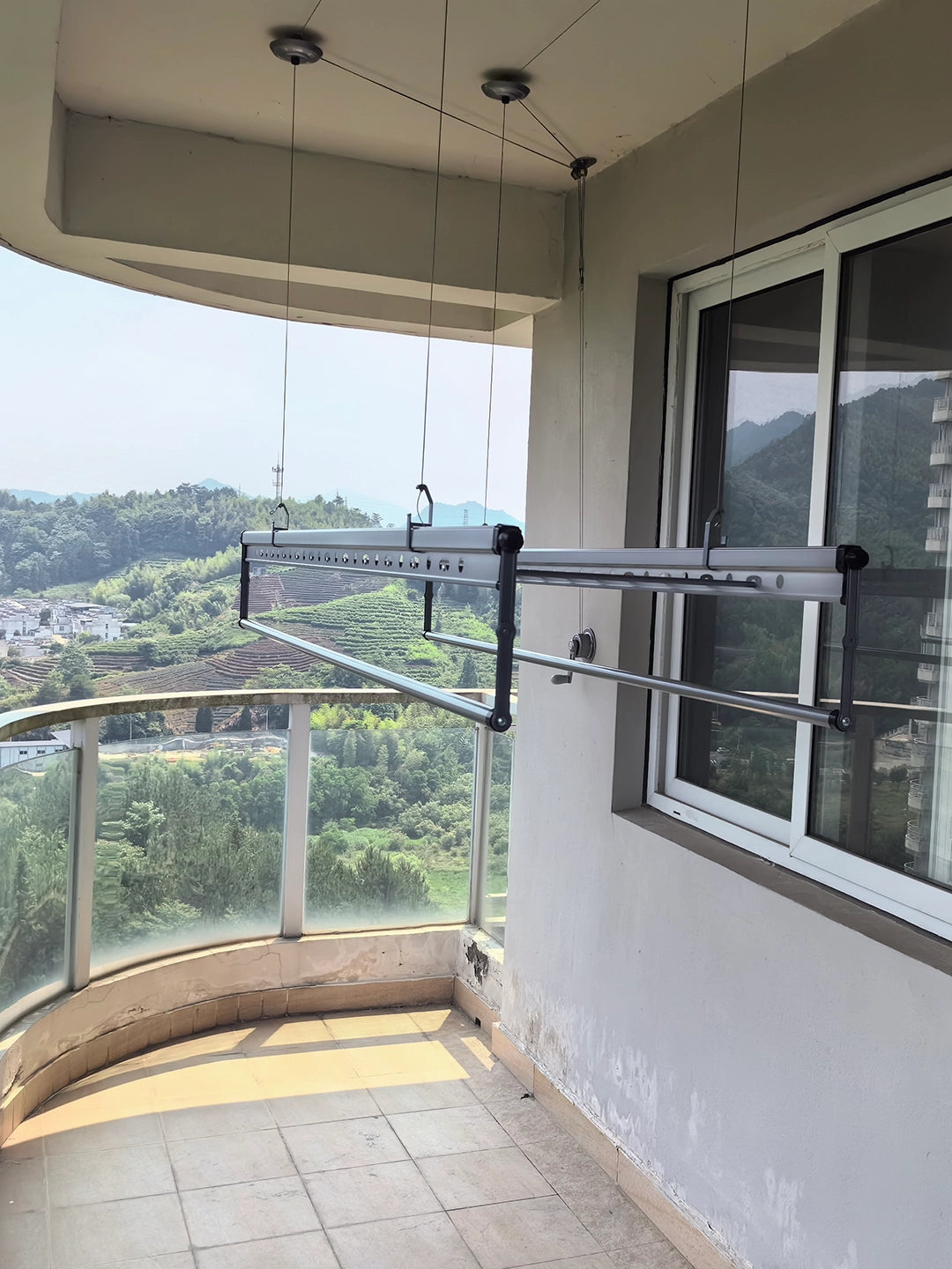 Square-Rod manual ceiling clothes airer lowered to working height on a sheltered balcony