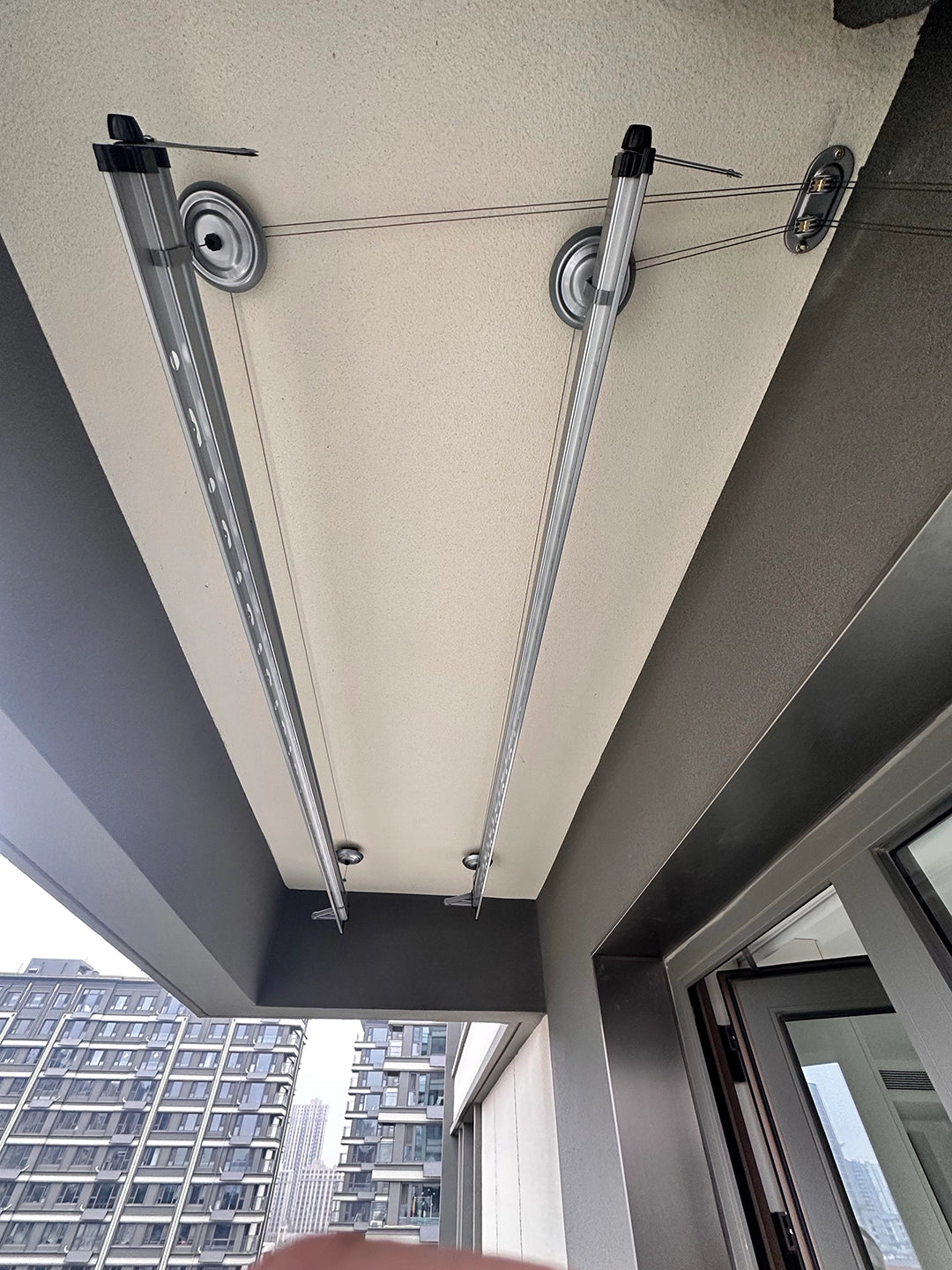 Customer-installed Square-Rod ceiling clothes airer viewed from below on a modern covered balcony