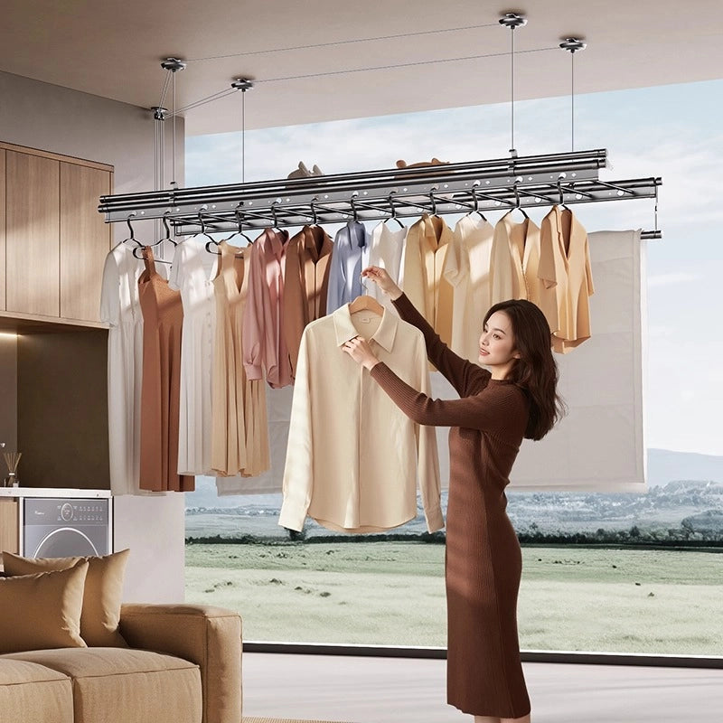 Woman hanging shirt under a ceiling-mounted clothes drying rack with baby rod and pulley system in a modern laundry room.