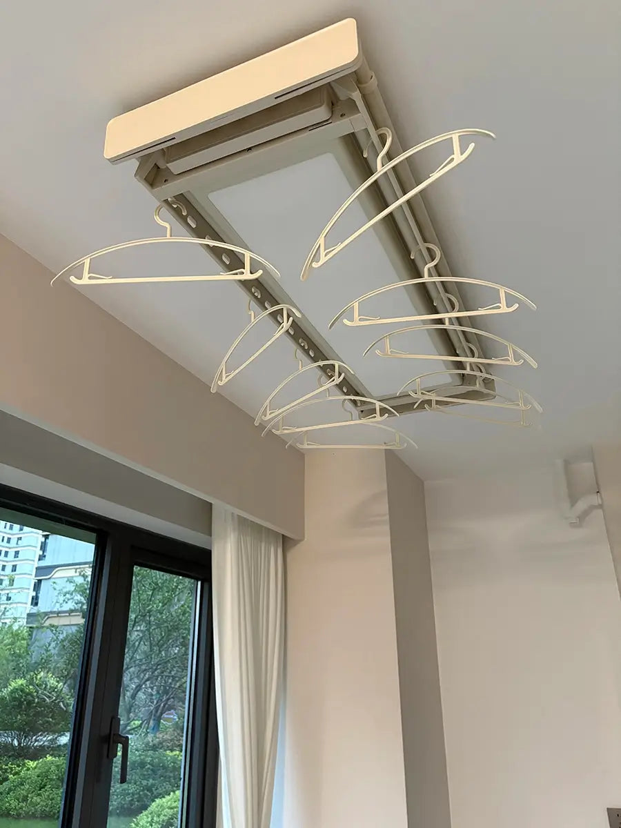 Easerack ceiling-mounted electric clothes drying rack installed near window, equipped with matching hangers.
