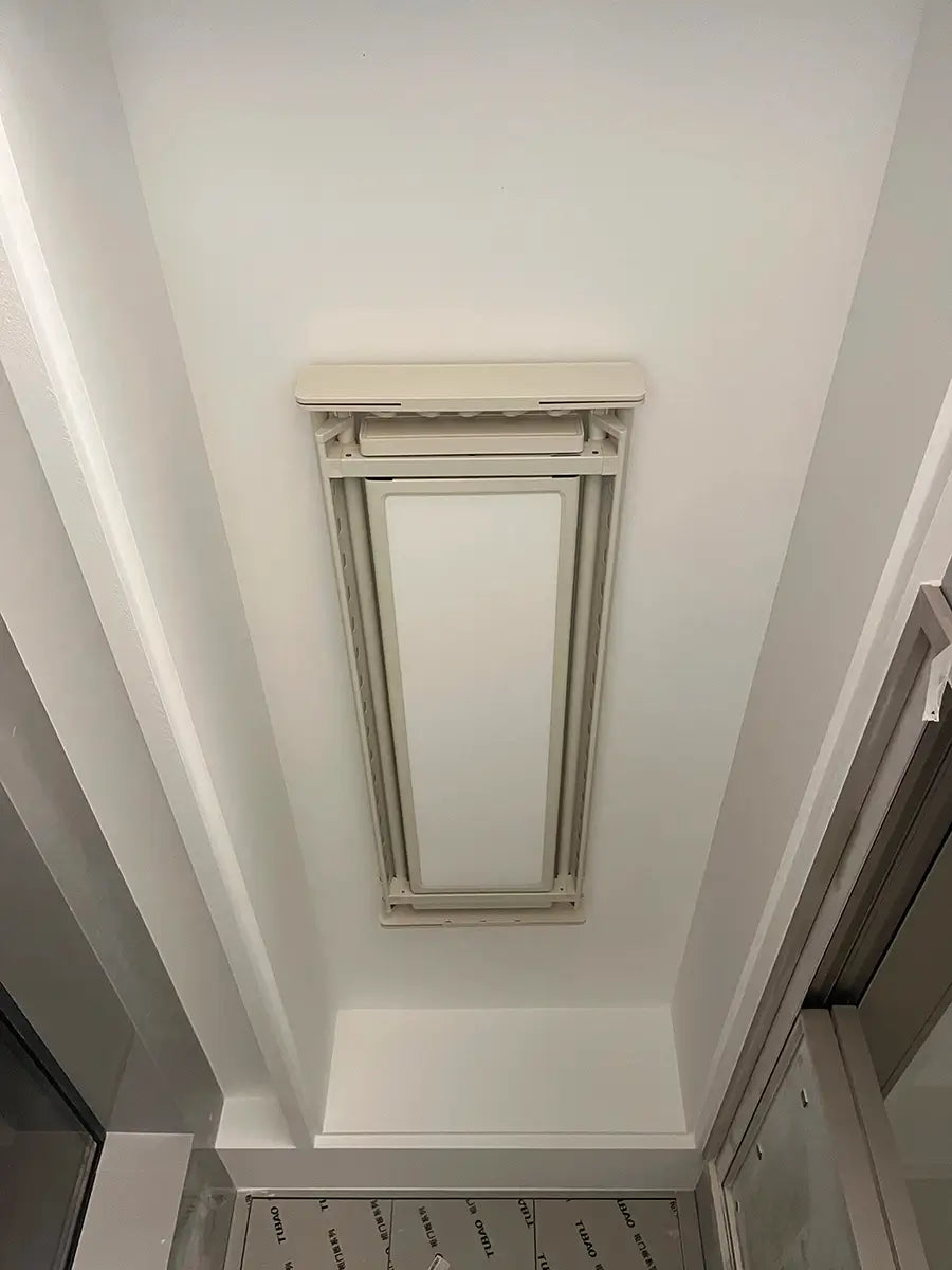 Minimalist EaseRack ceiling recessed electric clothes drying rack installed in narrow balcony.