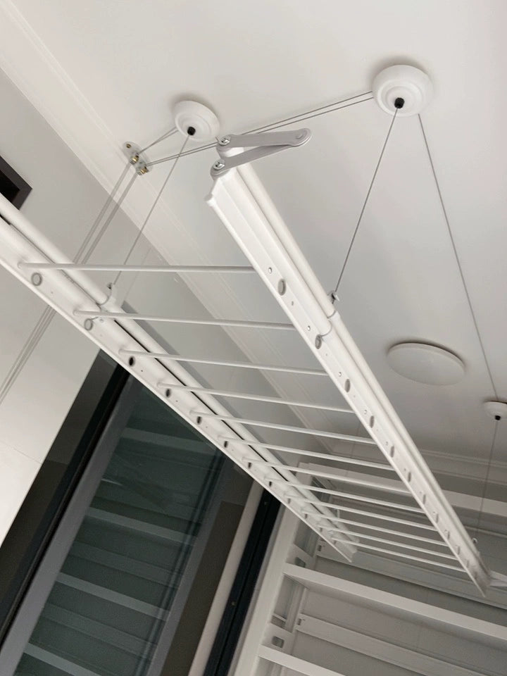 Nahaufnahme der Struktur eines Wäscheständers mit Handwinde, die einen stabilen Metallrahmen und ein Flaschenzugsystem zeigt.