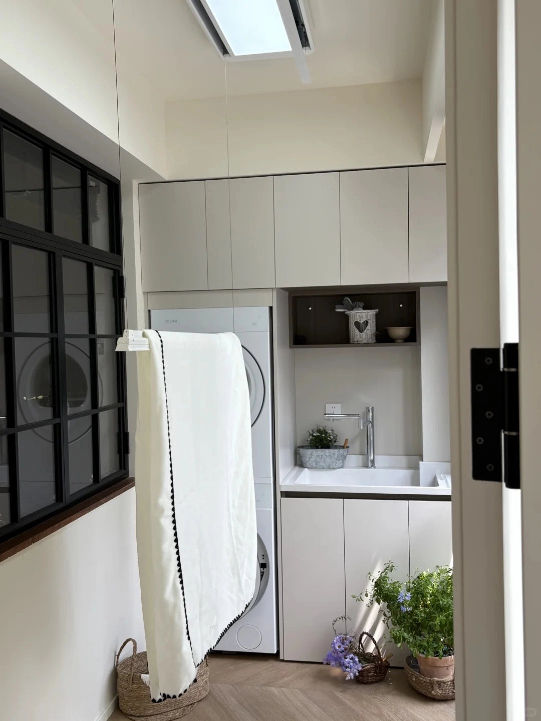 Ceiling clothes airer lowered with white laundry in a compact laundry area with stacked washer and dryer.