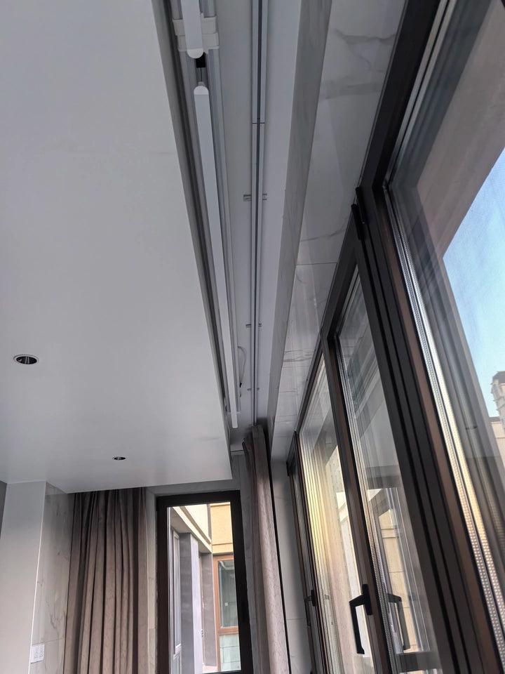 Ceiling mounted electric clothes drying rack installed neatly on a modern balcony ceiling, offering a space-saving laundry solution.
