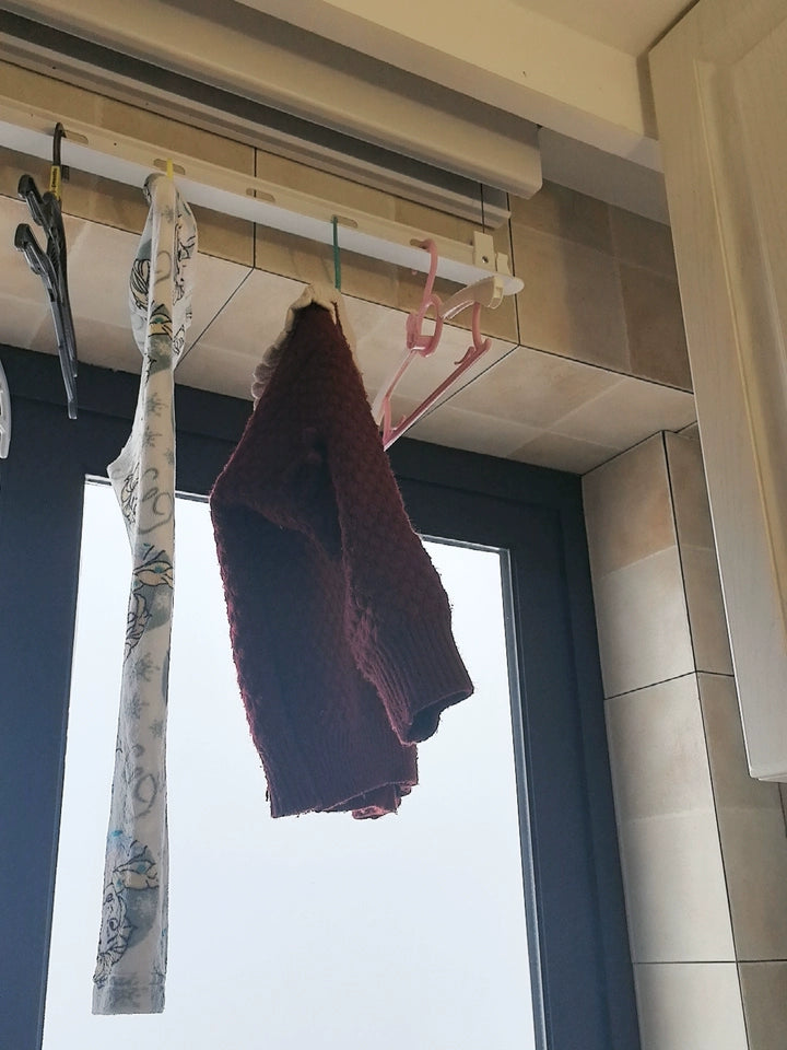 Ceiling mounted clothes drying rack holding sweaters and laundry, showing compact and practical space-saving drying solution.