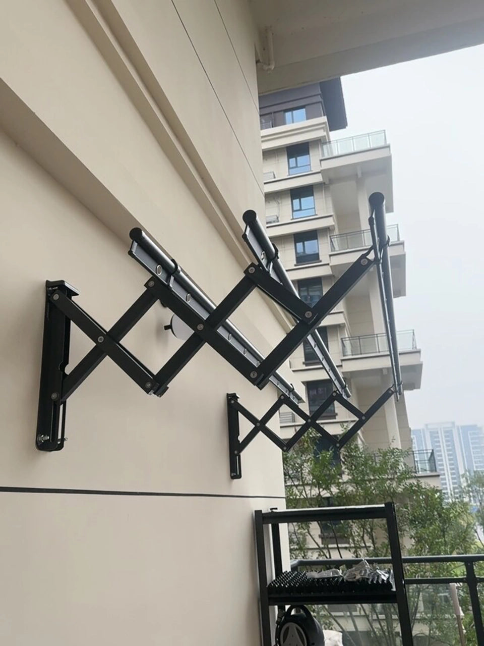 Real customer installation of an EaseRack wall-mounted retractable drying rack on a balcony wall.