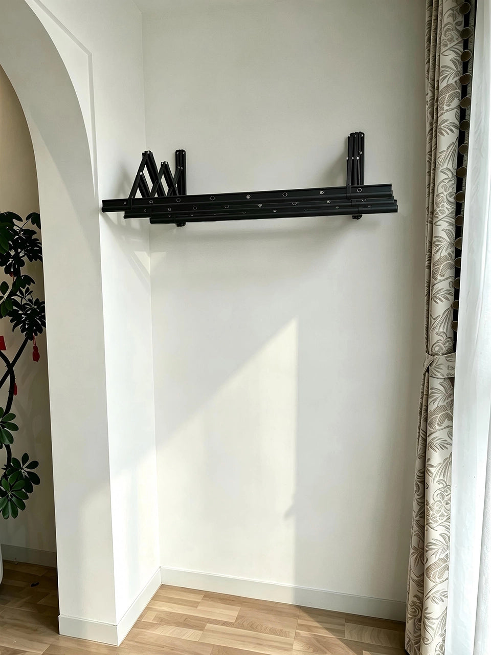 EaseRack wall-mounted retractable drying rack retracted against an indoor wall beside a window.