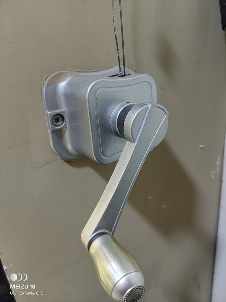 Wall-mounted manual hand winch with crank handle and lifting cable for a ceiling clothes airer.